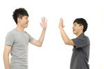 白い背景に韓国から来た2人のアジア人男性が互いにハイタッチをしている。