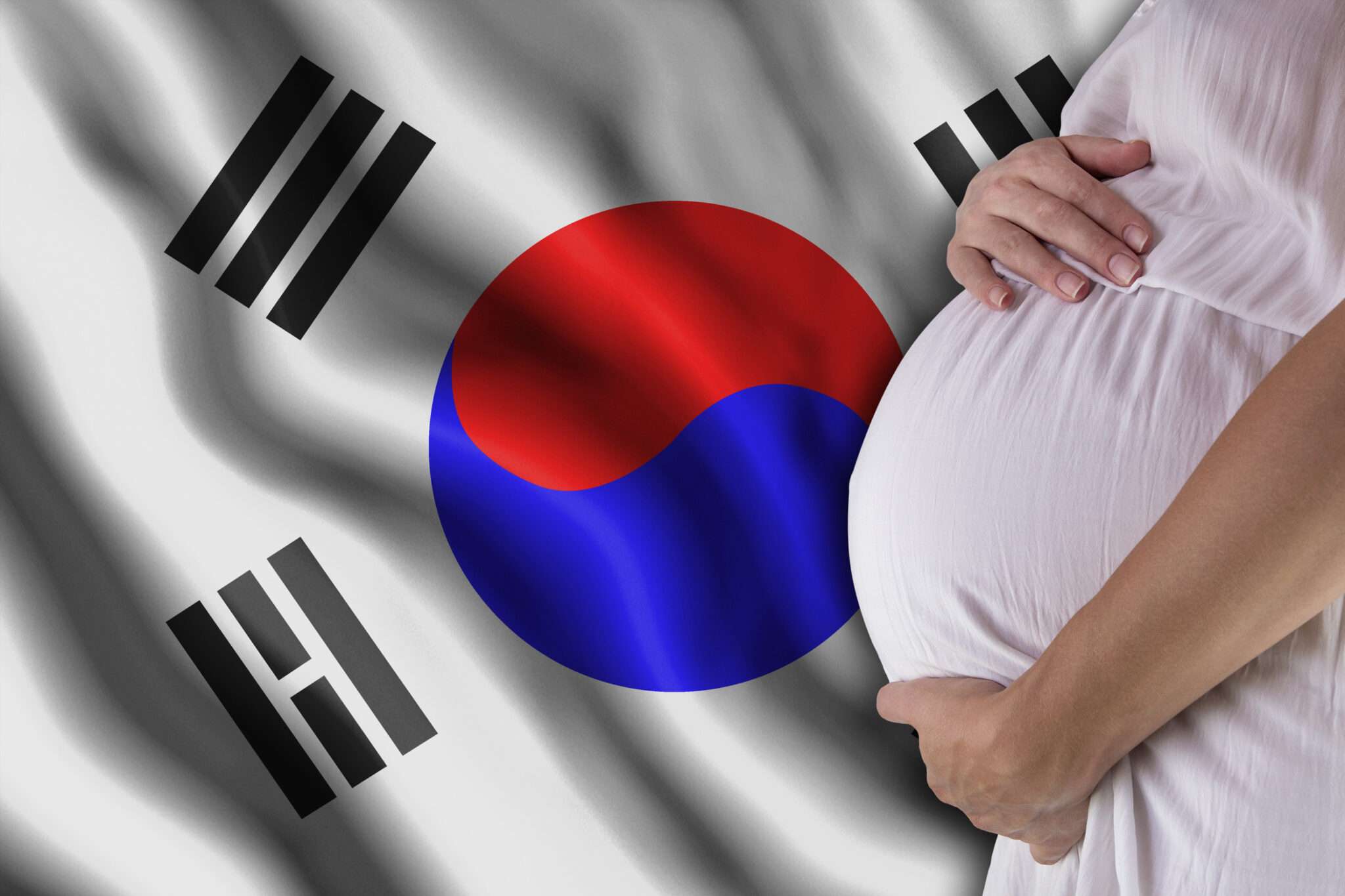 鮮やかな韓国国旗の前に誇らしげに立つ妊婦。