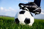韓国の影響を受けた芝生でサッカーボールを蹴っている人。