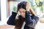 韓国で女性が頭を抱えて道を歩いている。