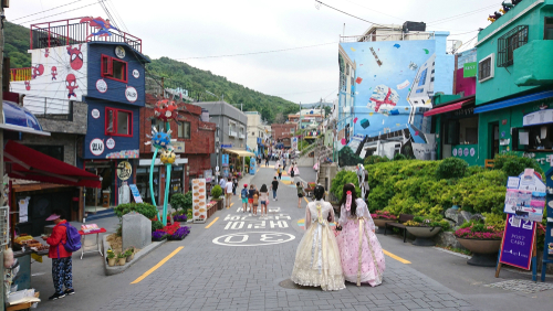 韓国のカラフルな建物が立ち並ぶ通りを2人の女性が歩いている。