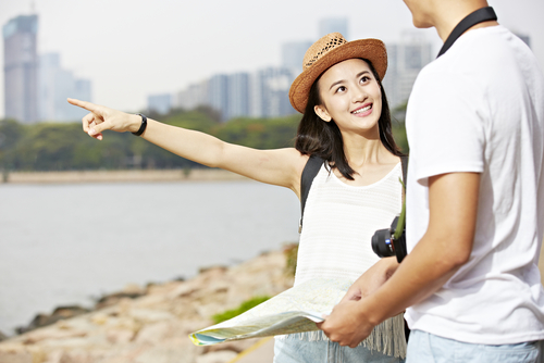 韓国の都市の前で、男性と女性が地図を指差している。