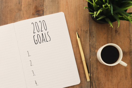 韓国の木製テーブルの上に2020年の目標が書かれたノートとコーヒー。