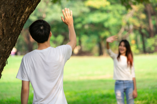 韓国の公園に立って手を振る男女。
