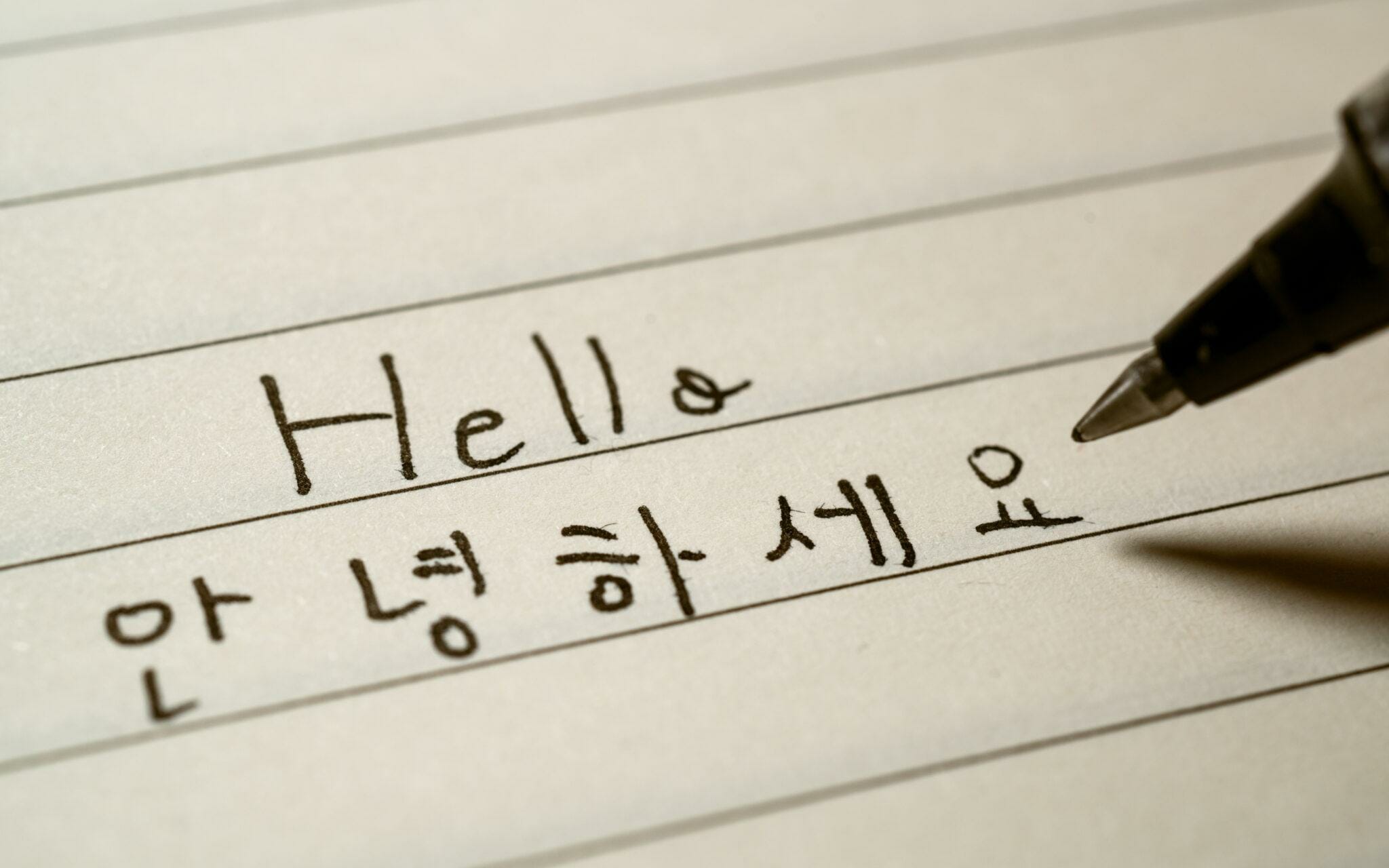 ペンが紙に韓国語で「こんにちは」と書いています。