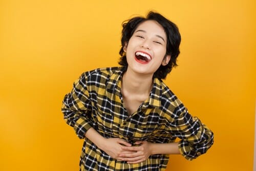 韓国の黄色い背景に笑う若い女性。
