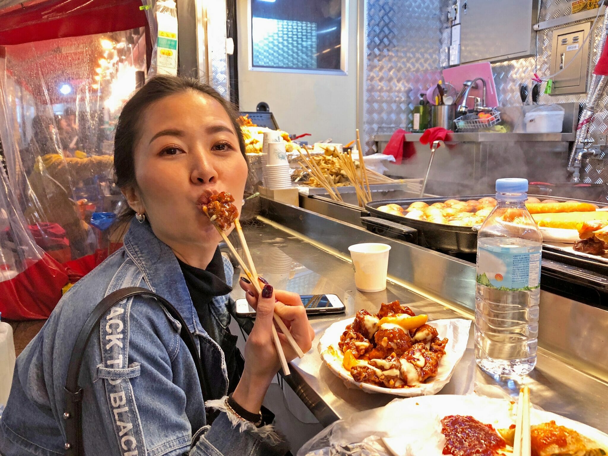 屋台でおいしい韓国料理を食べる女性。