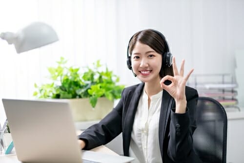 韓国のアジアのビジネス女性がラップトップの前で OK のジェスチャーをします。