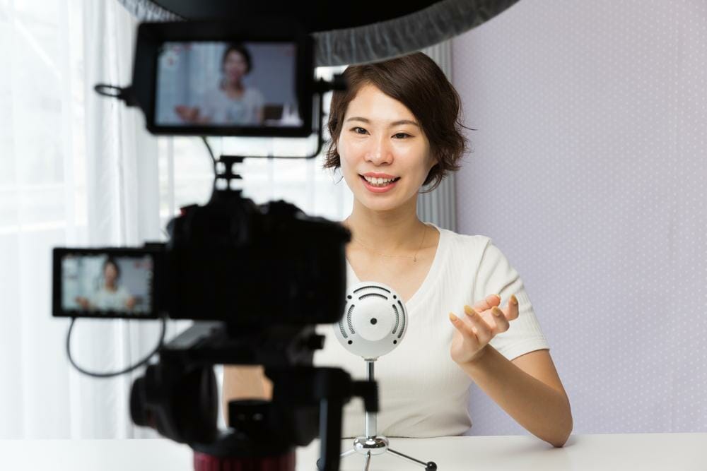 韓国から来た女性がテーブルの前でビデオカメラを持っています。