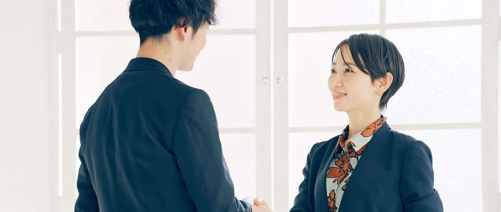 プロフェッショナルなパートナーシップを代表して握手する男性と女性。