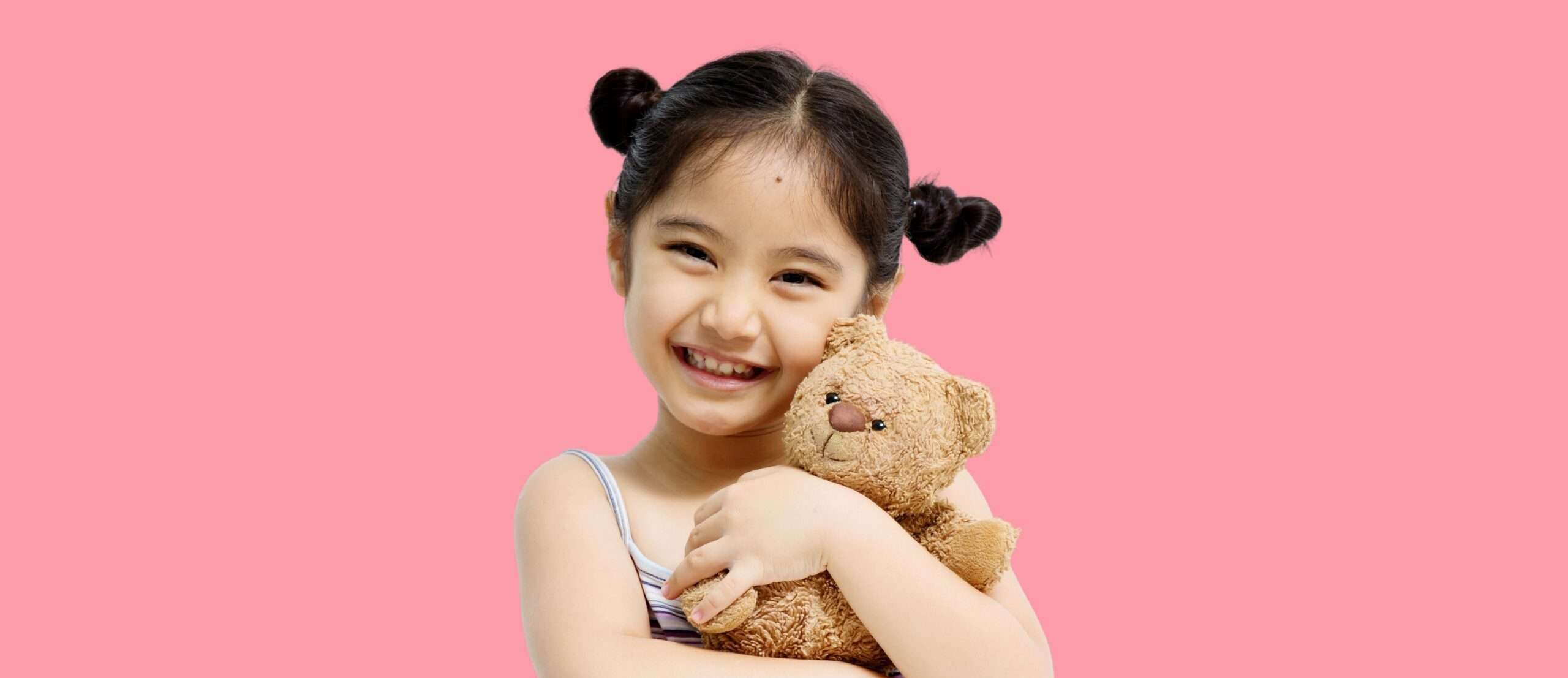韓国のピンクの背景にテディベアを持つ小さな女の子。
