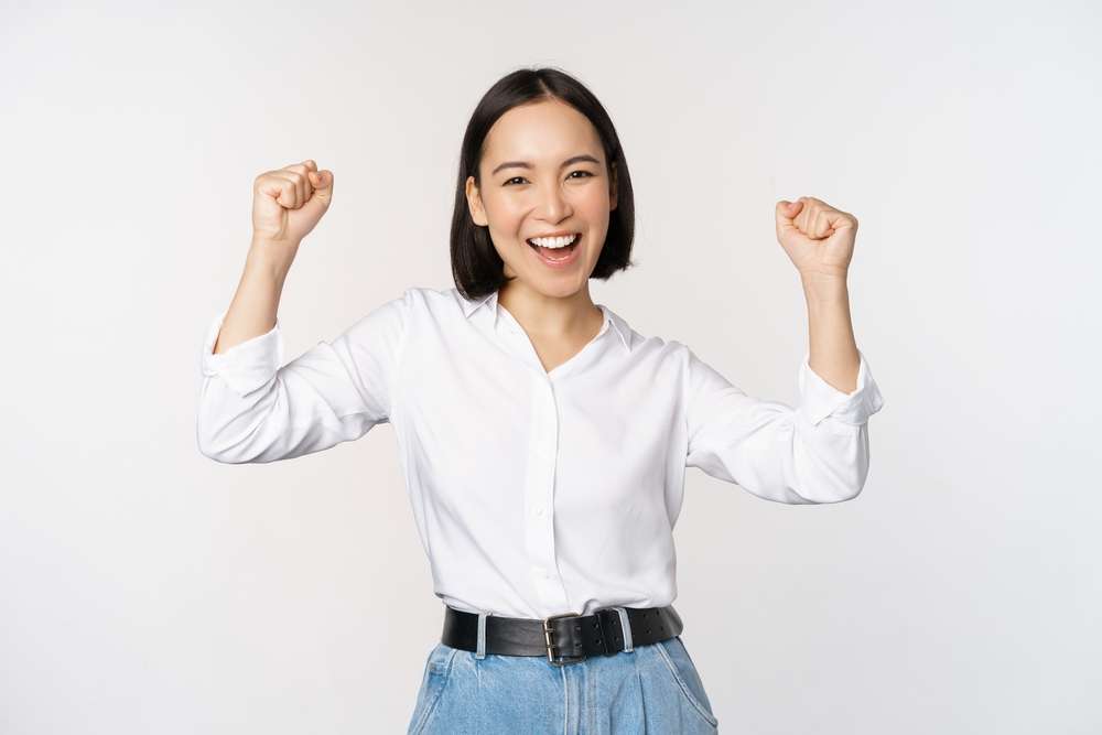白い背景に拳を上げて祝う韓国人女性。