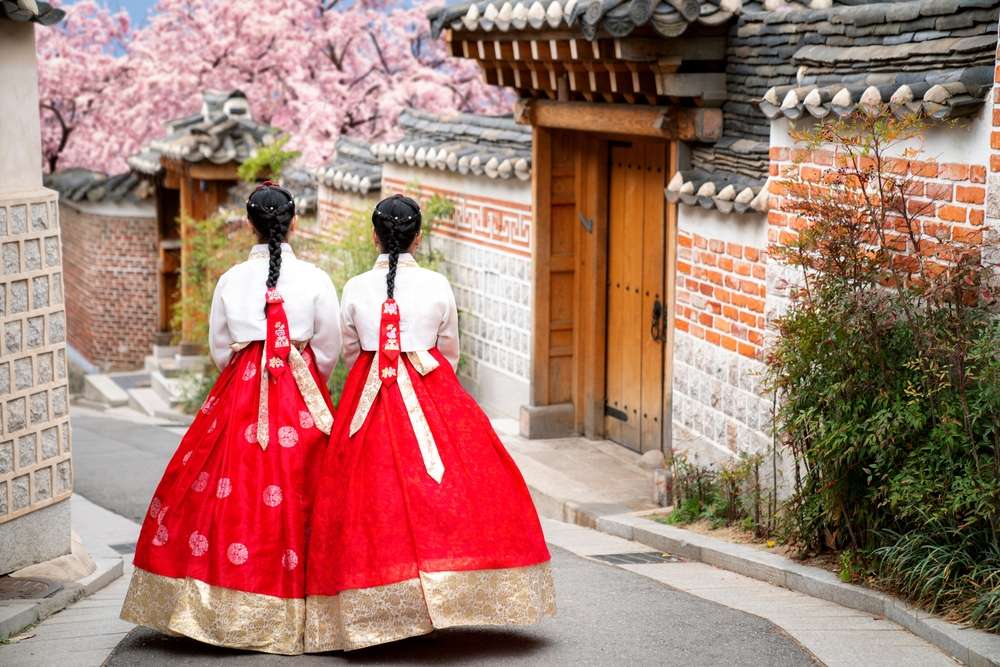韓国の伝統衣装を着た2人の韓国人女性が通りを歩いている。