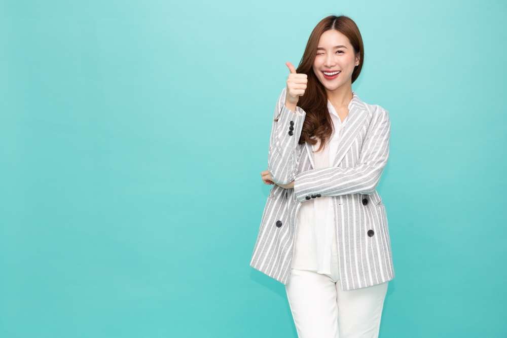 ストライプのスーツを着て親指を立てる韓国の女性。