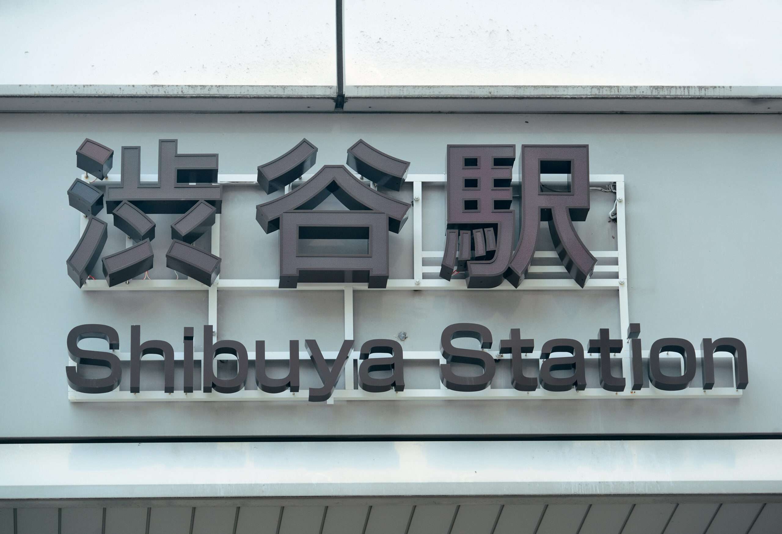 英語と日本語で「渋谷駅」と書かれた標識が、建物の正面に優雅に設置されています。