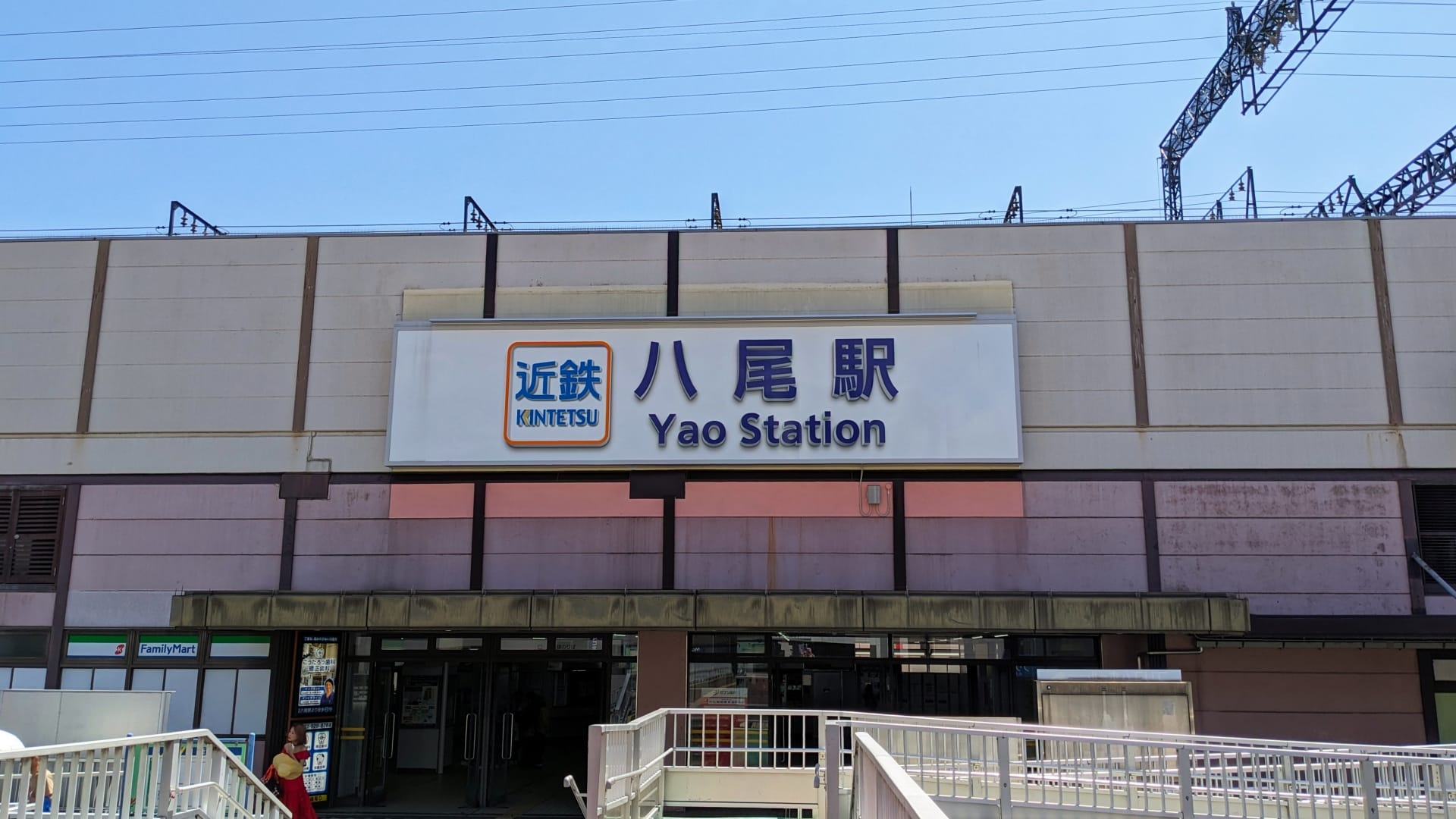 八尾駅舎の正面図。「KINTETSU」の看板とその下に入口があり、八尾の有名な韓国語教室マンツーマンの近くに位置しています。.
