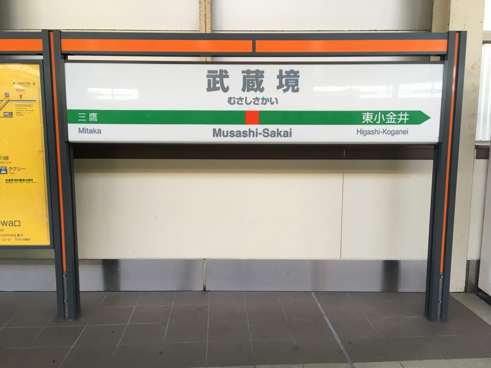 武蔵境の駅名標。左側に三鷹、右側に東小金井の方向が日本語と英語で書かれています。近くで次回の韓国語教室マンツーマンセッションに向かう人に最適です。.