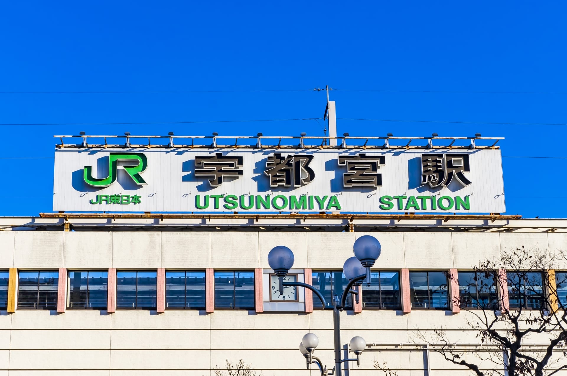 澄んだ青空に、JRのロゴが入った宇都宮駅の標識が堂々と立っています。近くには、この活気に満ちた街で韓国語を学びたい人に最適な韓国語教室マンツーマンがあります。.