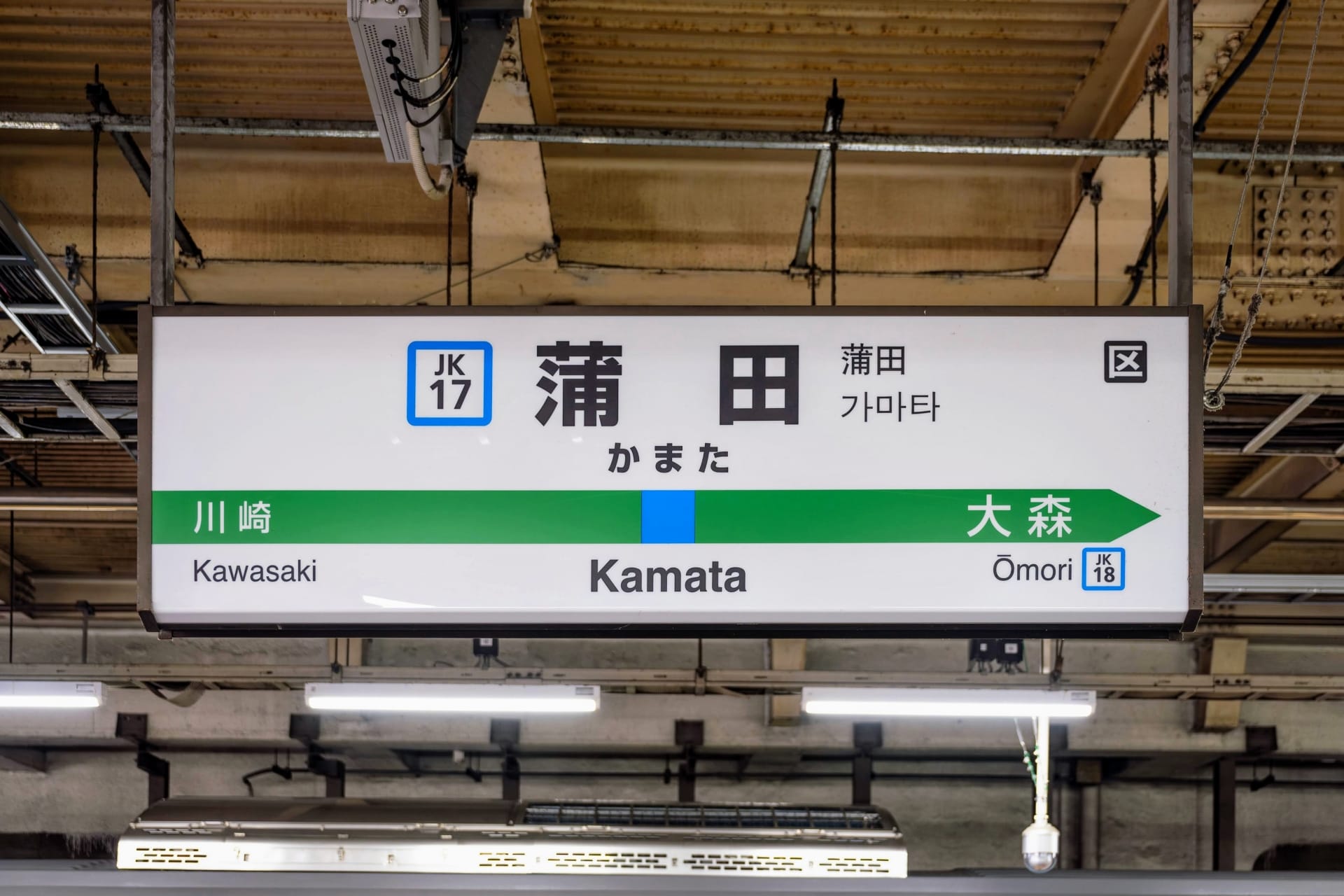 駅の案内板には、川崎、蒲田、大森方面への路線が日本語、韓国語、英語で表示されています。天井と照明が、賑やかな風景の上に魅力的な雰囲気を醸し出しています。.