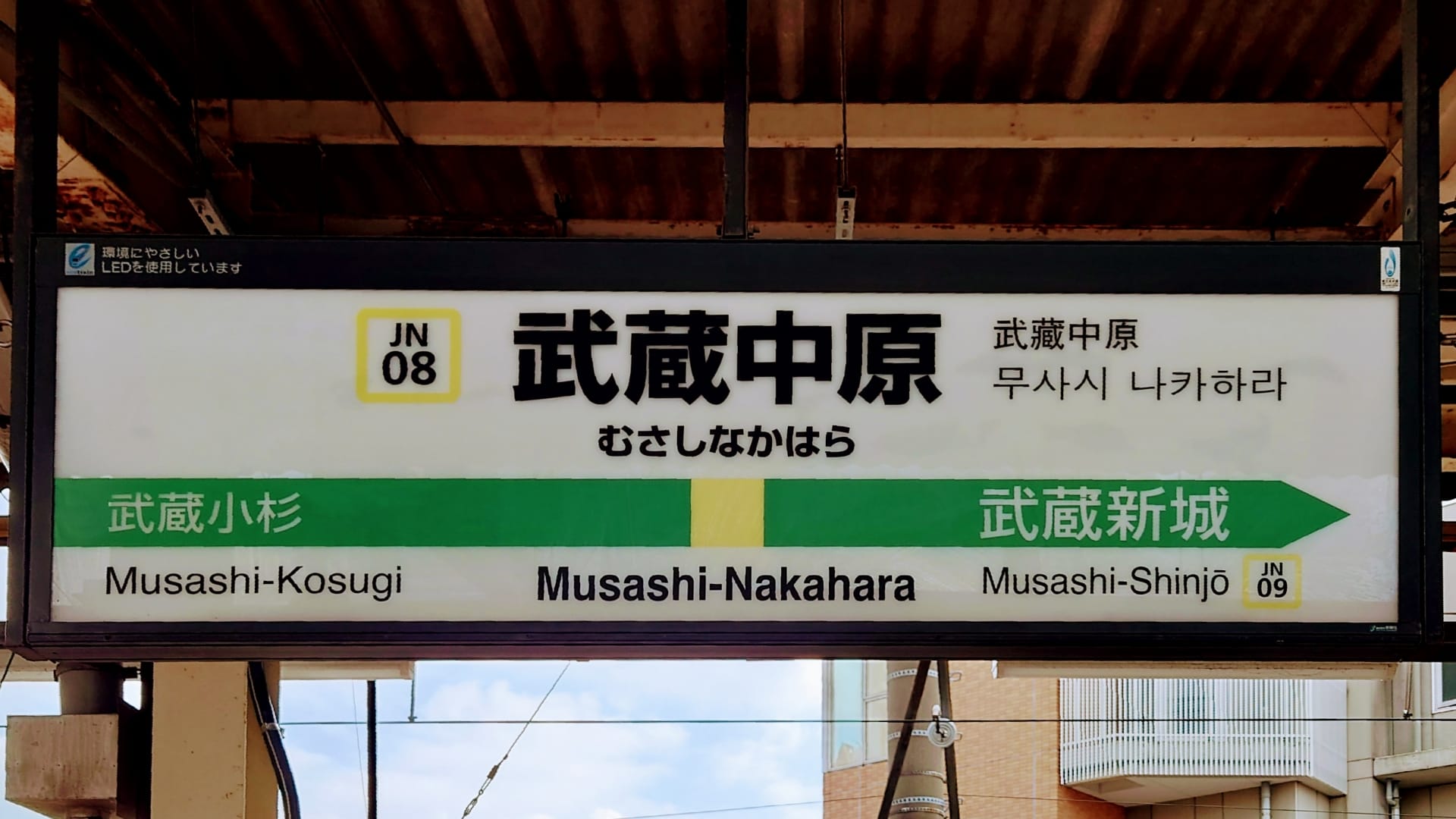 駅名標には武蔵中原（武蔵中原）を中心に、武蔵小杉と武蔵新城への方向が表示されています。標識には日本語、英語で書かれ、言語学習者向けに韓国語教室マンツーマンへの敬意が示されています。.
