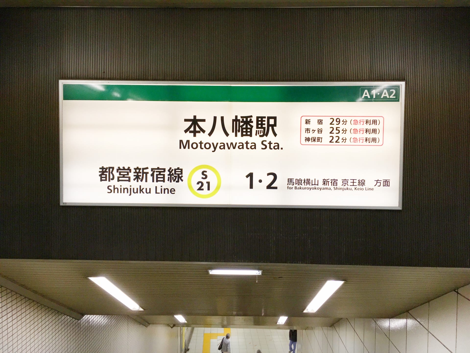 新宿線本八幡駅の標識には、行き先と所要時間が表示されています。階段は下に向かっており、そこから人が降りてきて、おそらく近くの本八幡韓国語教室マンツーマンに行き、個別の言語レッスンを受けているのでしょう。.