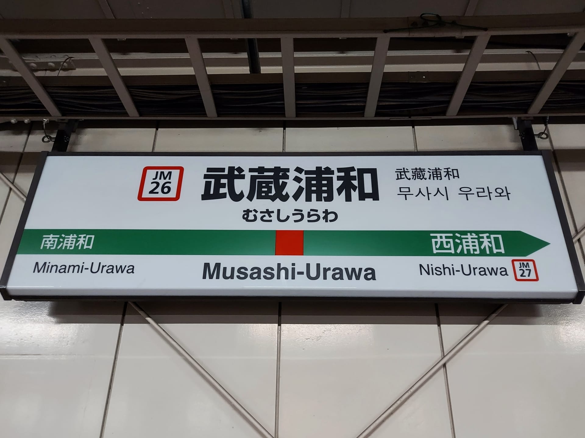 武蔵浦和の駅名標には、日本語、韓国語、英語で「Musashi-Urawa」と表記されています。方向矢印は旅行者を南浦和 (左) と西浦和 (右) に案内しており、韓国語教室マンツーマンに向かう人やこの地域を探索する人に最適です。.