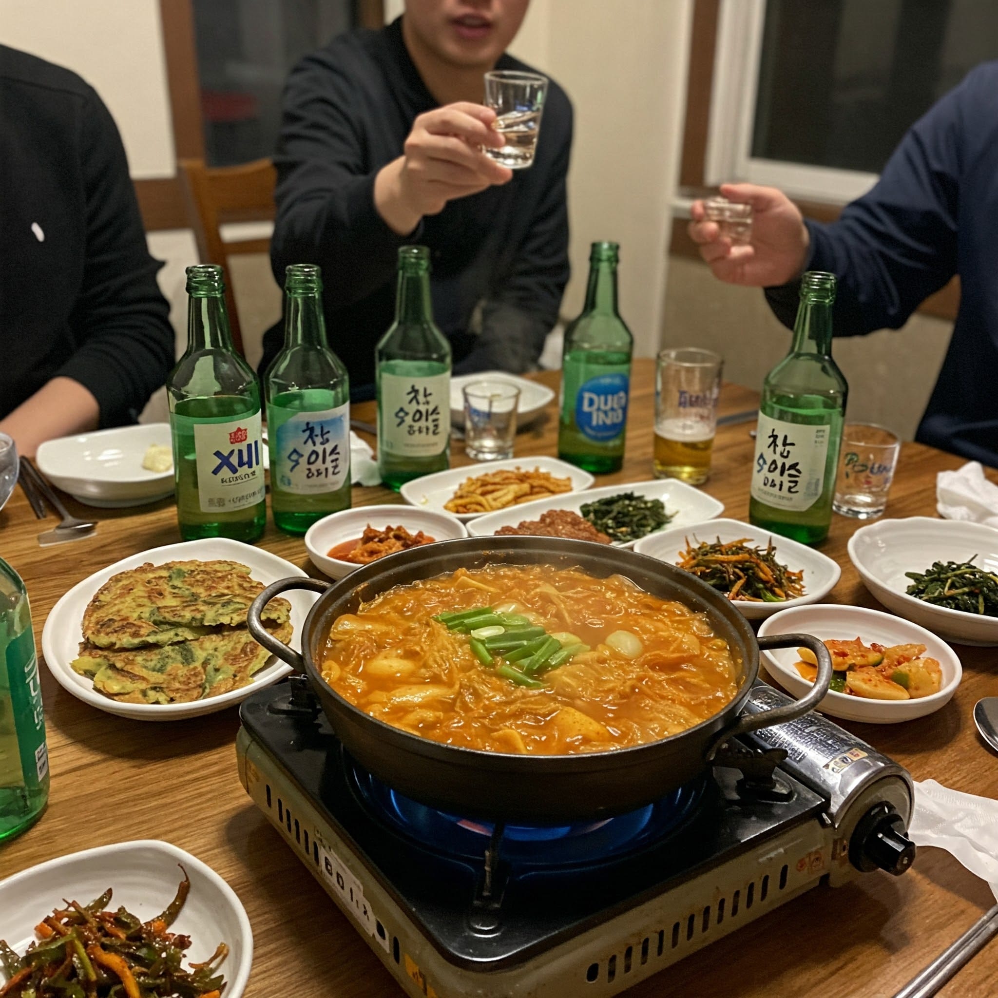 テーブルに並んだ韓国料理（サムギョプサル、チヂミ）と焼酎