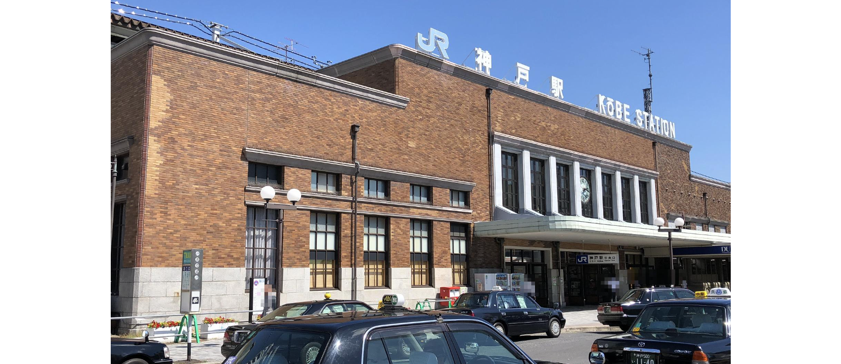 神戸駅のレンガ造りの駅舎には大きな窓があり、日本語と英語の看板が掲げられている。.