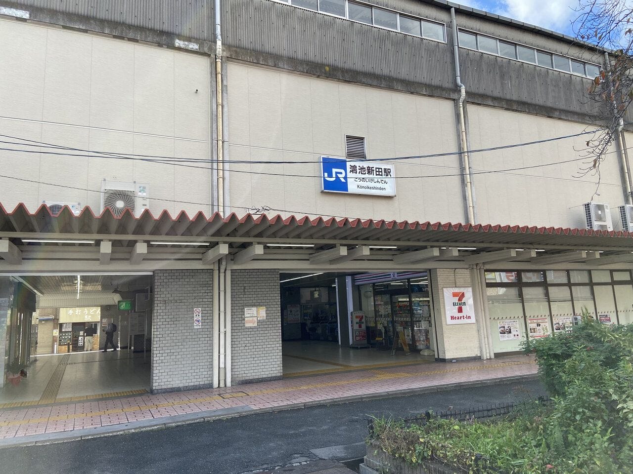 日本のJR腰越駅の外観。右手にセブン-イレブン、中央が駅の入り口。.
