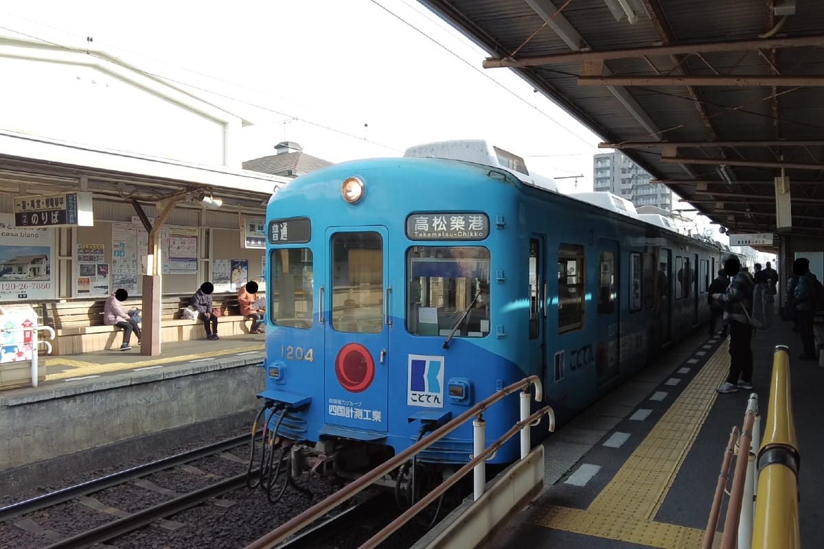 ブルートレインが駅のホームに停車している。駅には屋根があり、日本語の看板が見える。.