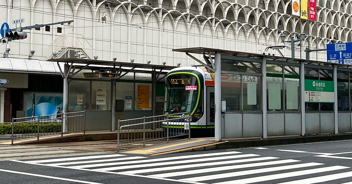 都市部の横断歩道の隣にある屋根付きの路面電車の停留所に、近代的な路面電車が停車した。.